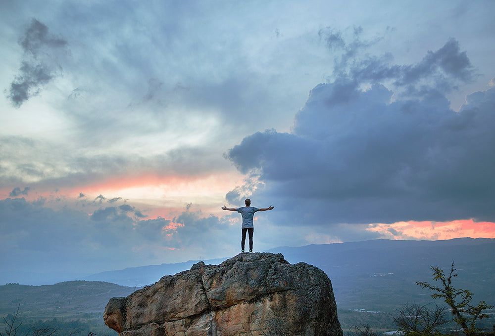 Man with arms stretched out wide on a cliff