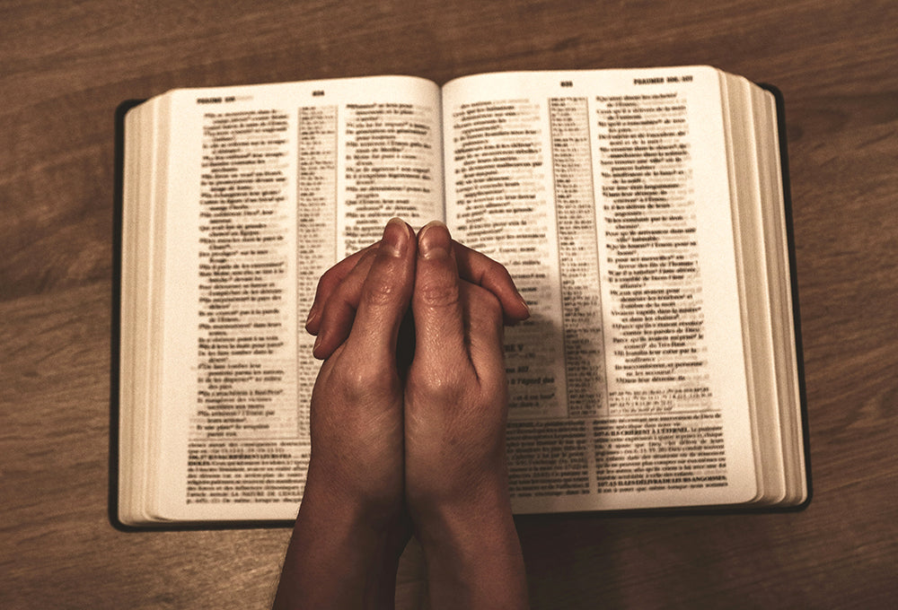 Hands folded in prayer on bible