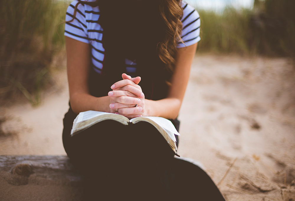 Girl praying with her bible in nature