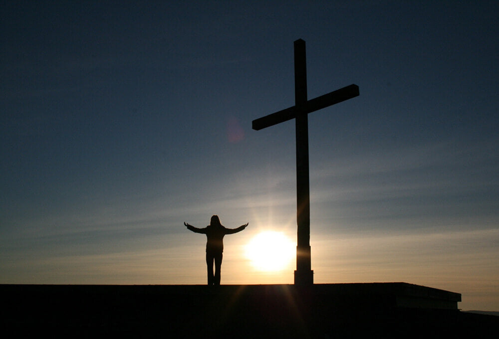 Hands lifted in worship against a glowing sky