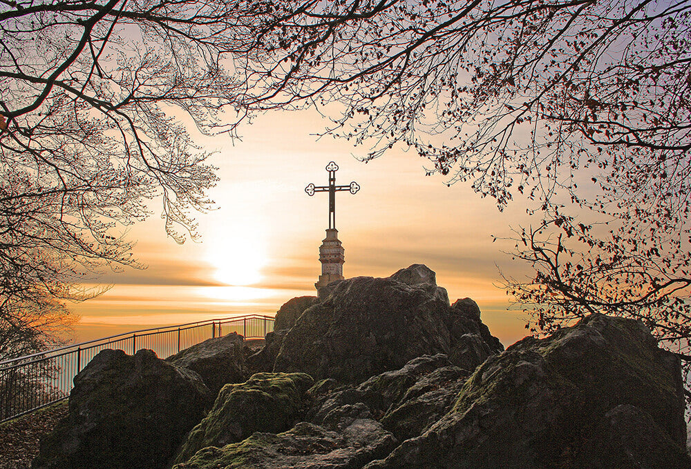 cross on the rocky hill with beautiful flowering trees around it