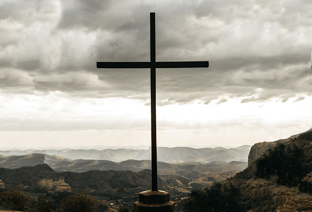 Cross standing on a hill with overcast skies signifying the true love of Jesus