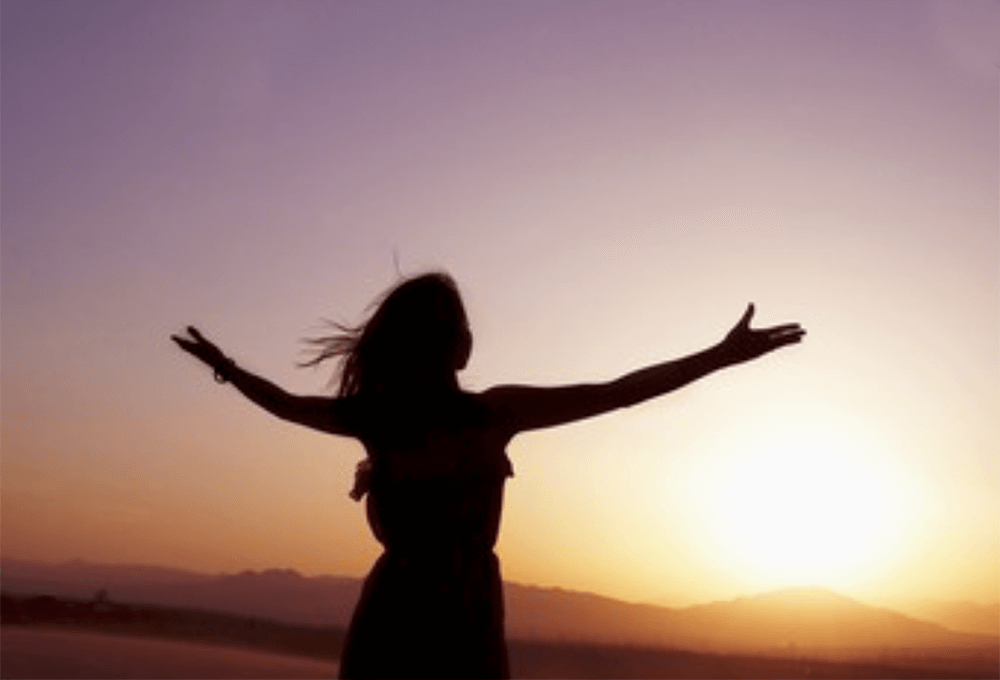 Woman spreading her arms in thanks and praise to God