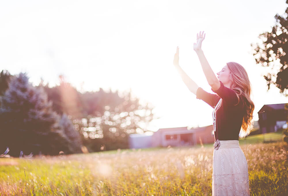 Woman raising hands in air to express her gratitude to God