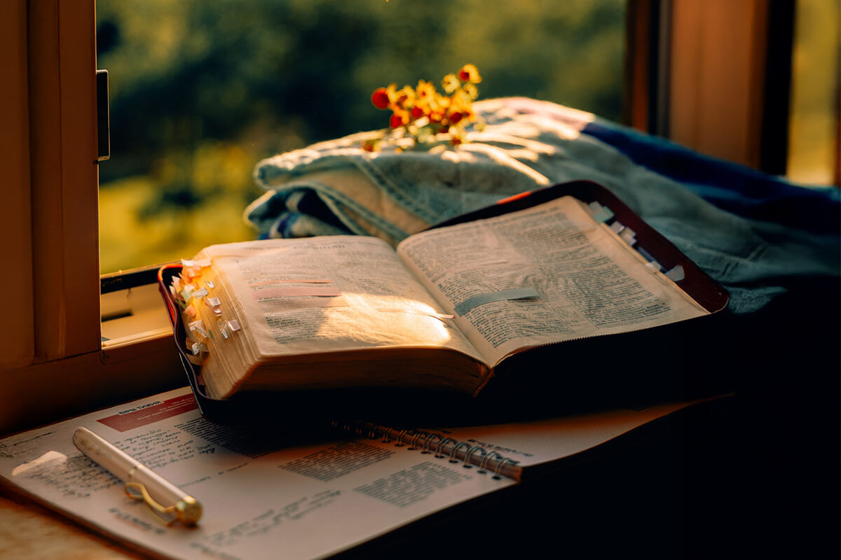 A Bible and journal beside a bright window, ready for prayer and reflection on how to live a life of faith.