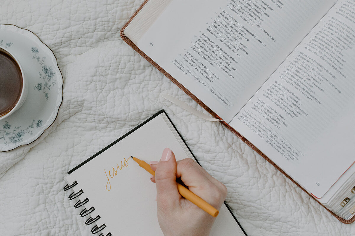 An open Bible, cream journal being written in, and a cup of coffee inviting reflection on God's strength.