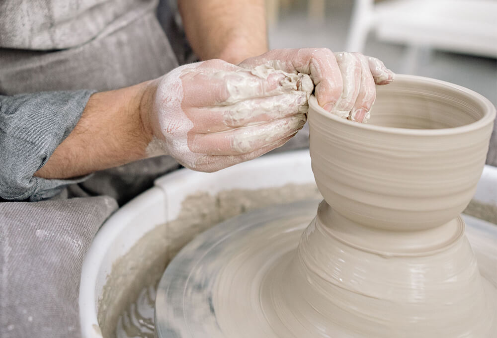 Potter sitting at a pottery wheel creating a bowl