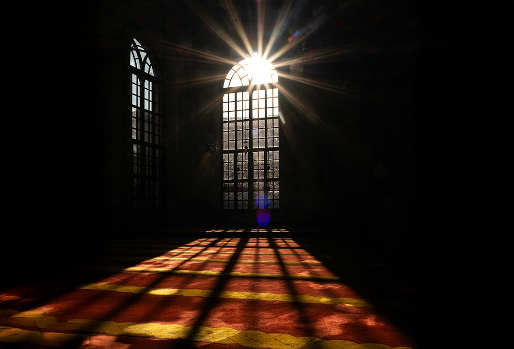 Sunlight shining through arched window, reflecting across the textured wood surface