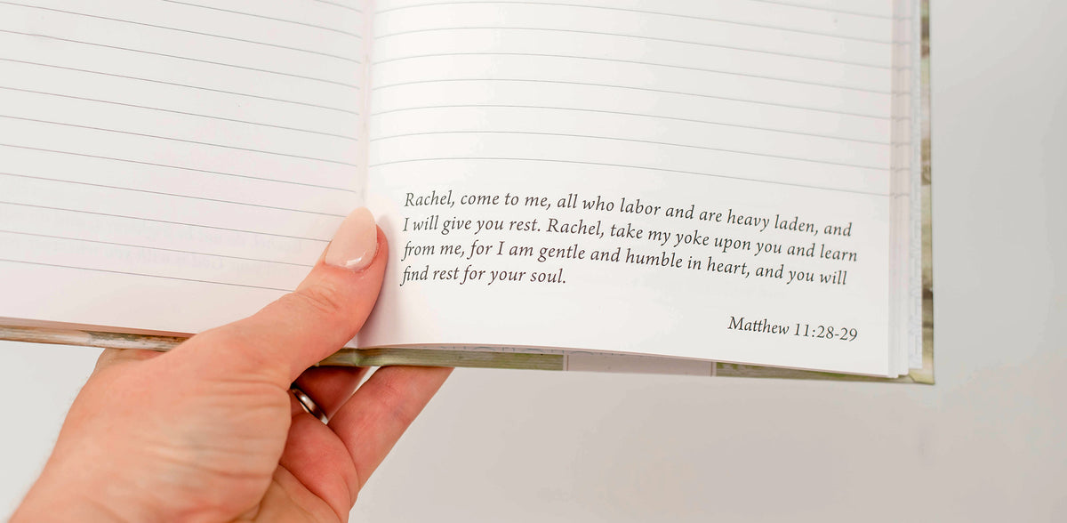 A hand holding an open Paper Sunday journal; the printed verse begins “Rachel, come to me, all who labor”