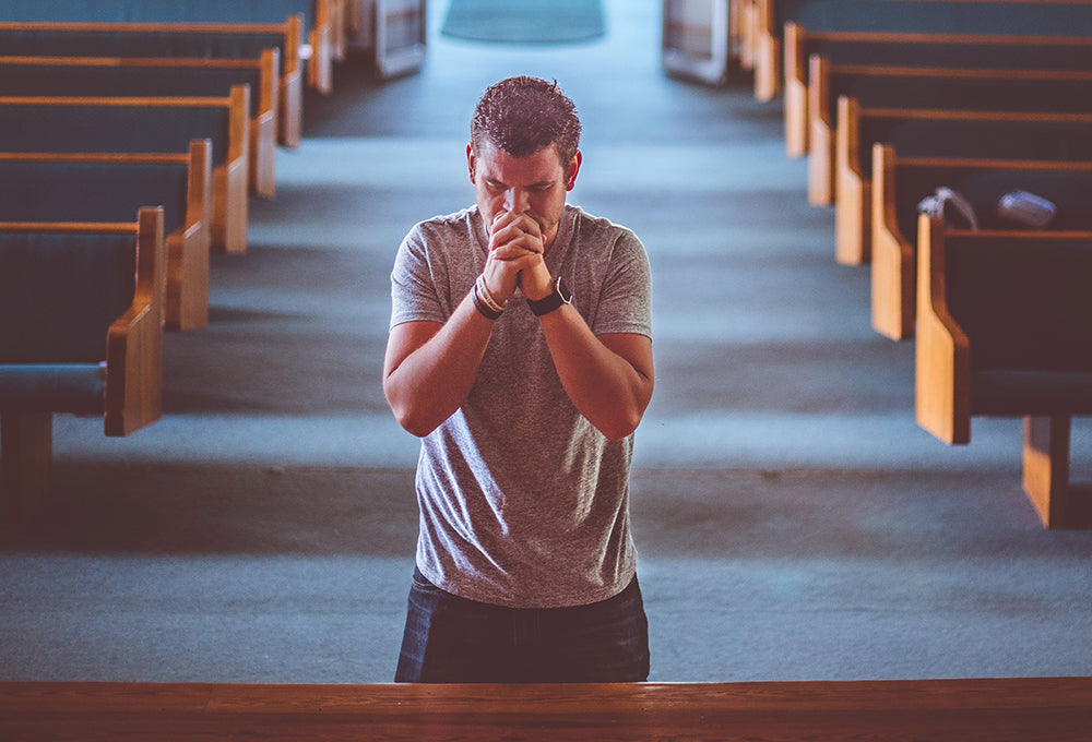 Man praying quietly in reflection in church pews