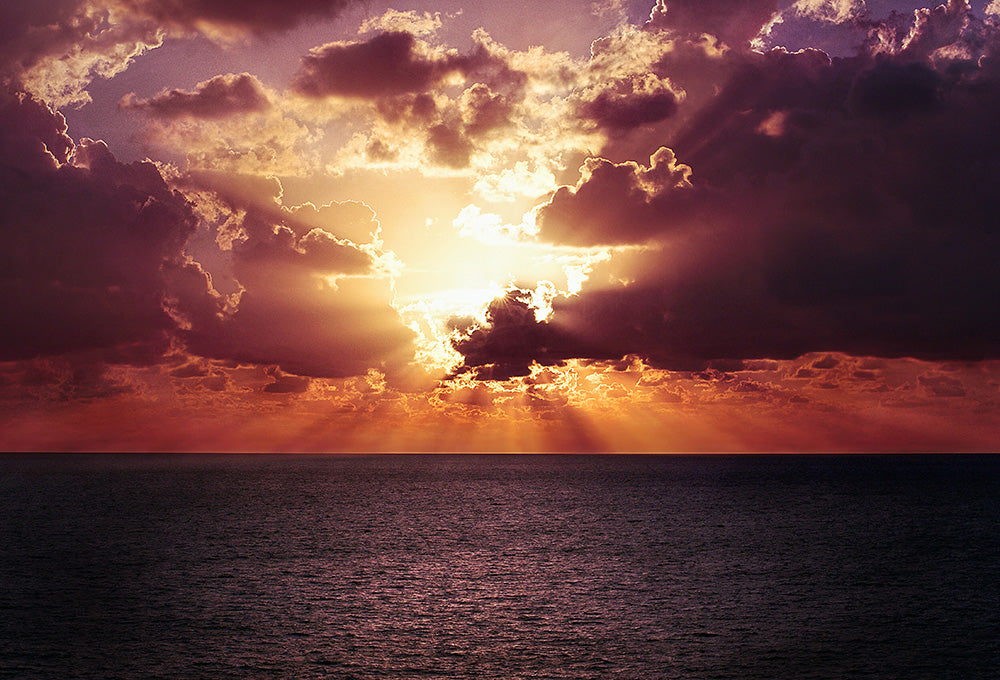 Amazing sunset with sun beaming through clouds on the ocean