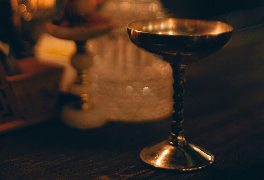 An ancient brass cup on a dimly lighted wood table