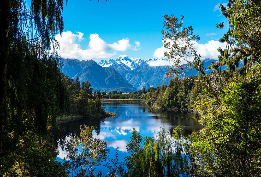 Beautiful lake with trees, majestic mountains and a blue sky