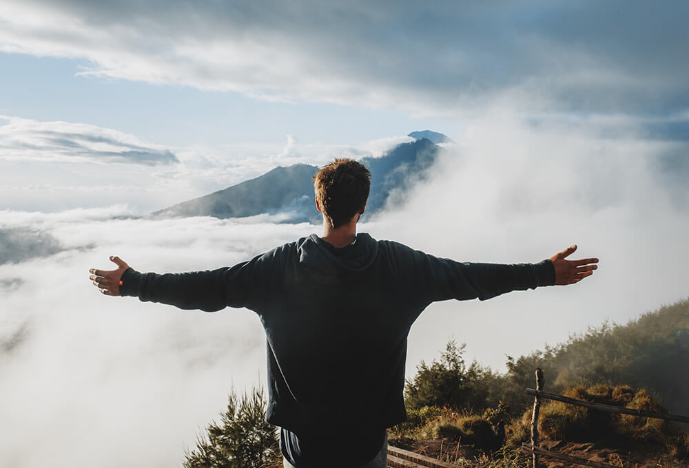 Silhouette with arms raised under open sky
