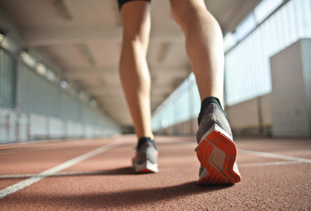 runner's legs in a stadium, focusing on footwear and athletic motion
