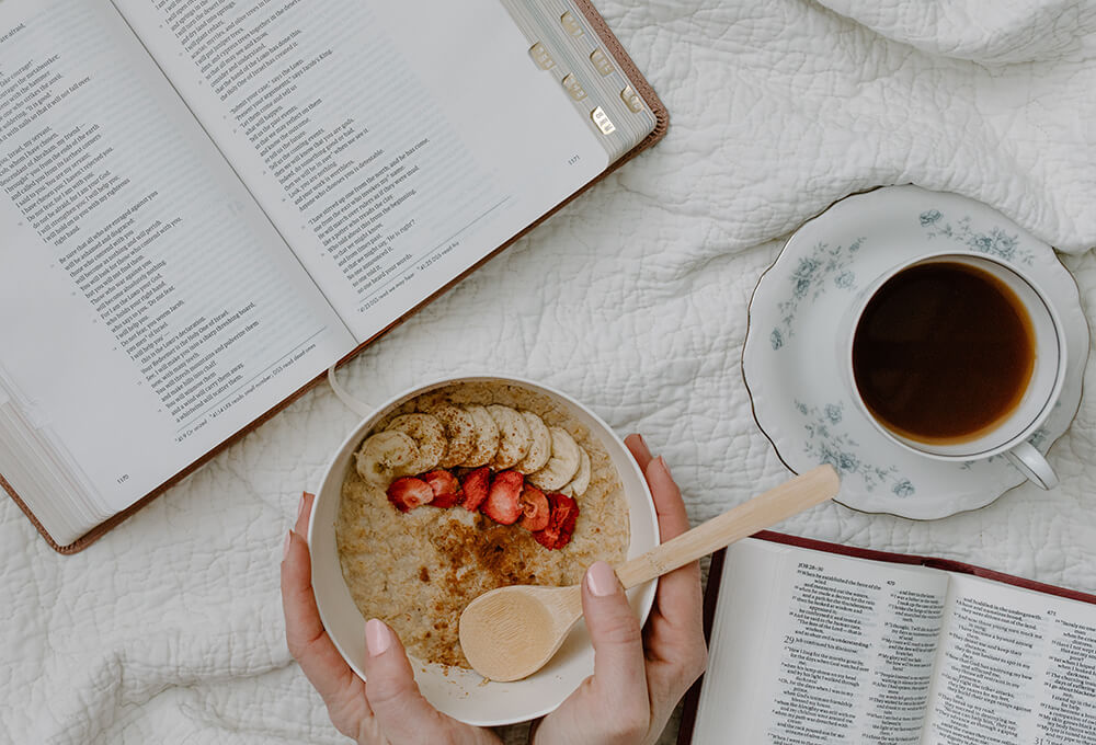 Woman having oatmeal and coffee while studying the bible and journaling