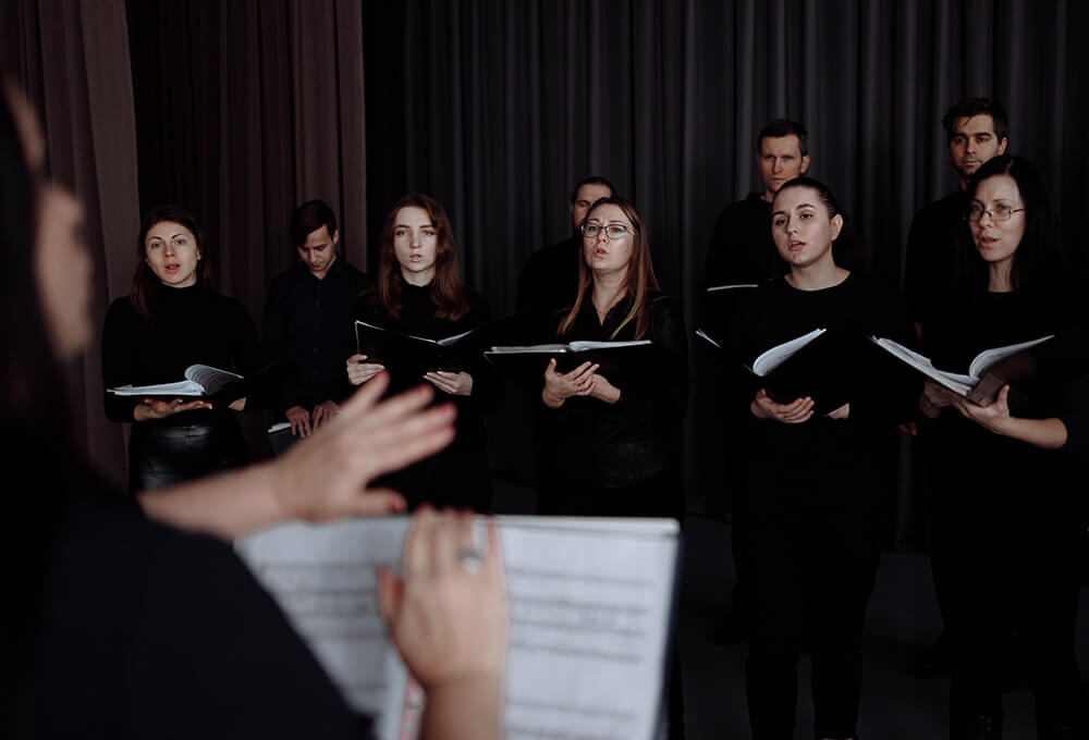 A choir group singing in unison, led by a conductor.