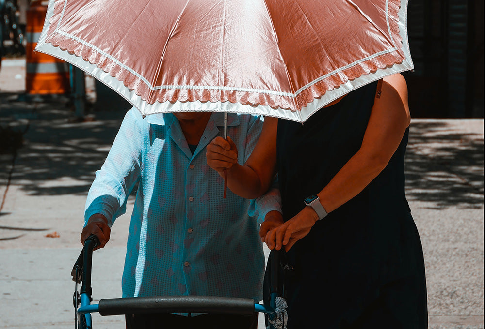 woman holding an umbrella and helping an elderly woman, being an example of the golden rule