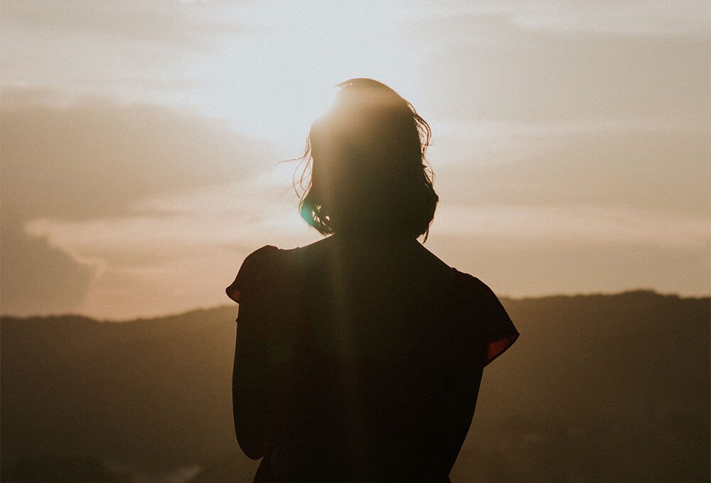 Woman looking toward a bright horizon