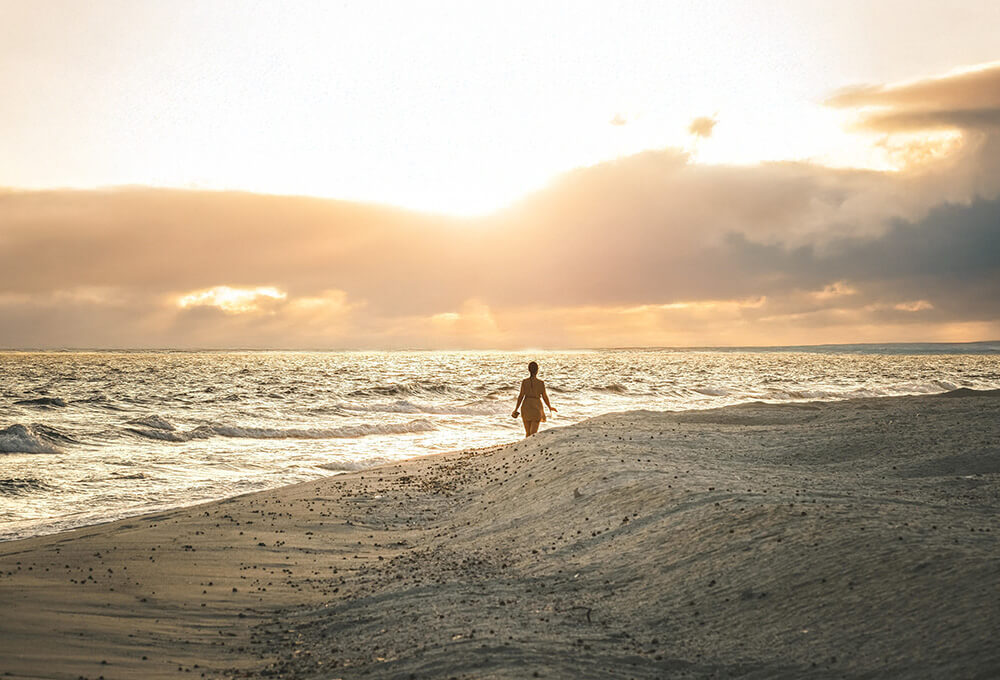 woman enjoying a solitary walk on the beach during a beautiful sunrise