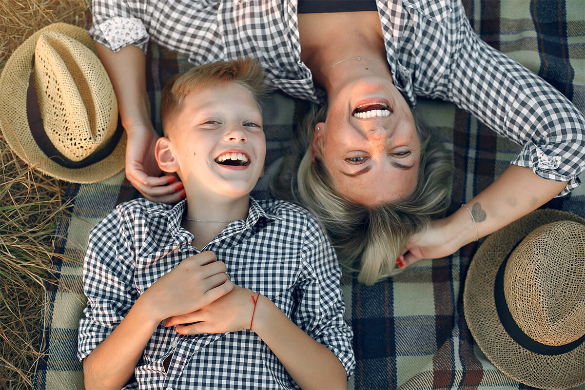 Woman and her son smiling peacefully in warm sunlight, reflecting joy and hope found in God.
