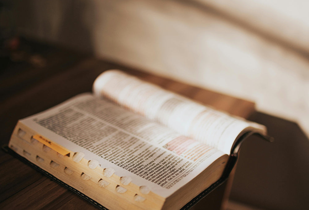 Open bible with notes and highlights in scripture open on a wood desk