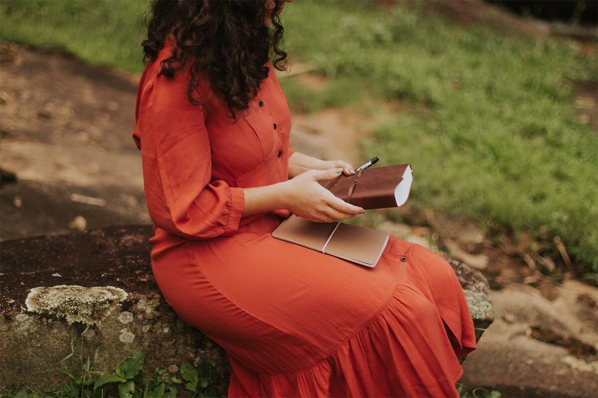 Woman journaling in a peaceful sunlit space, reflecting on her identity and God's promises