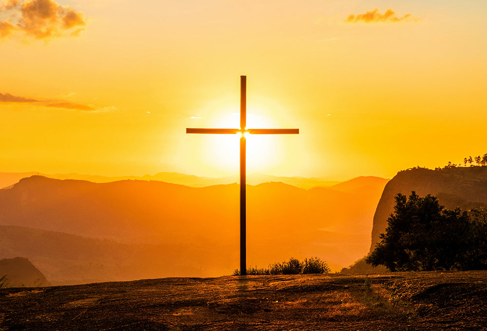 Cross on hill with a beautiful orange and yellow sunset