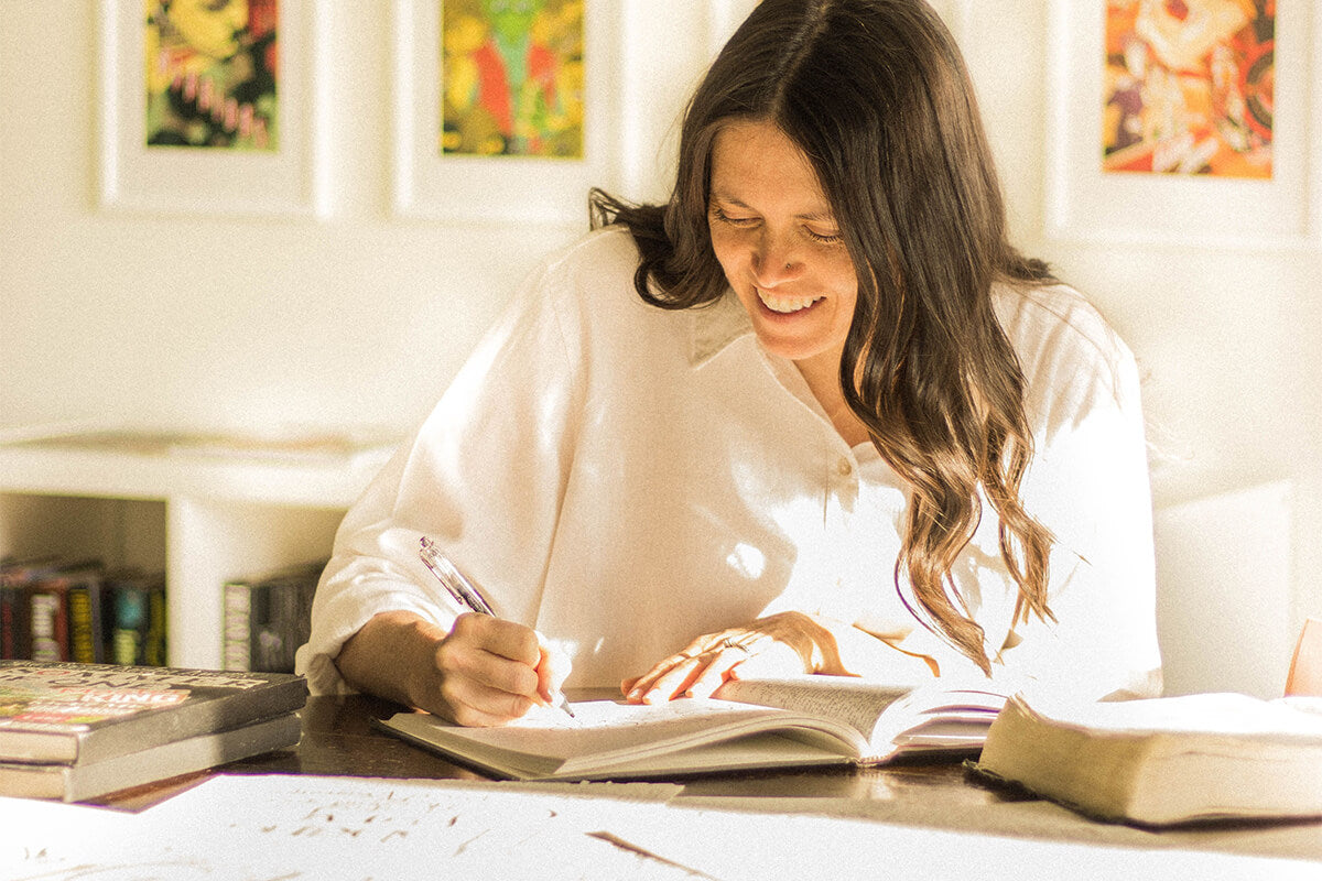 Woman reflecting on Scripture with an open Bible and journal, finding encouragement in her identity in Christ.