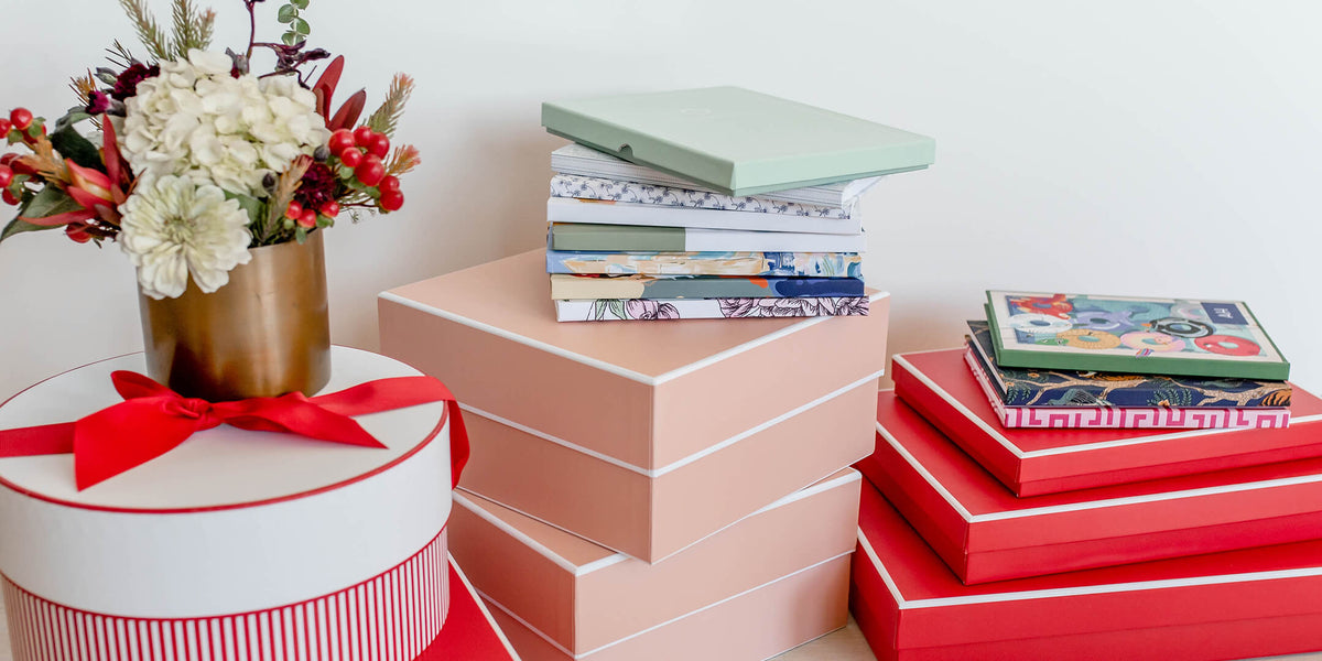 multiple christian planners stacked on pink and red boxes with flowers for accent