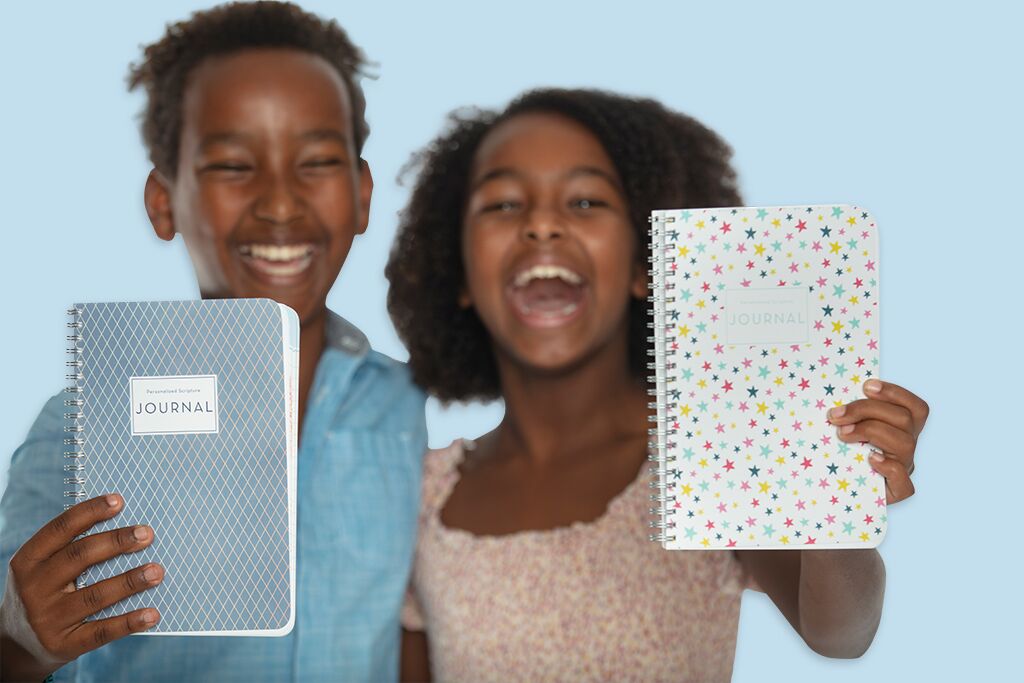 Two kids hugging and laughing as they show their personalized scripture journals