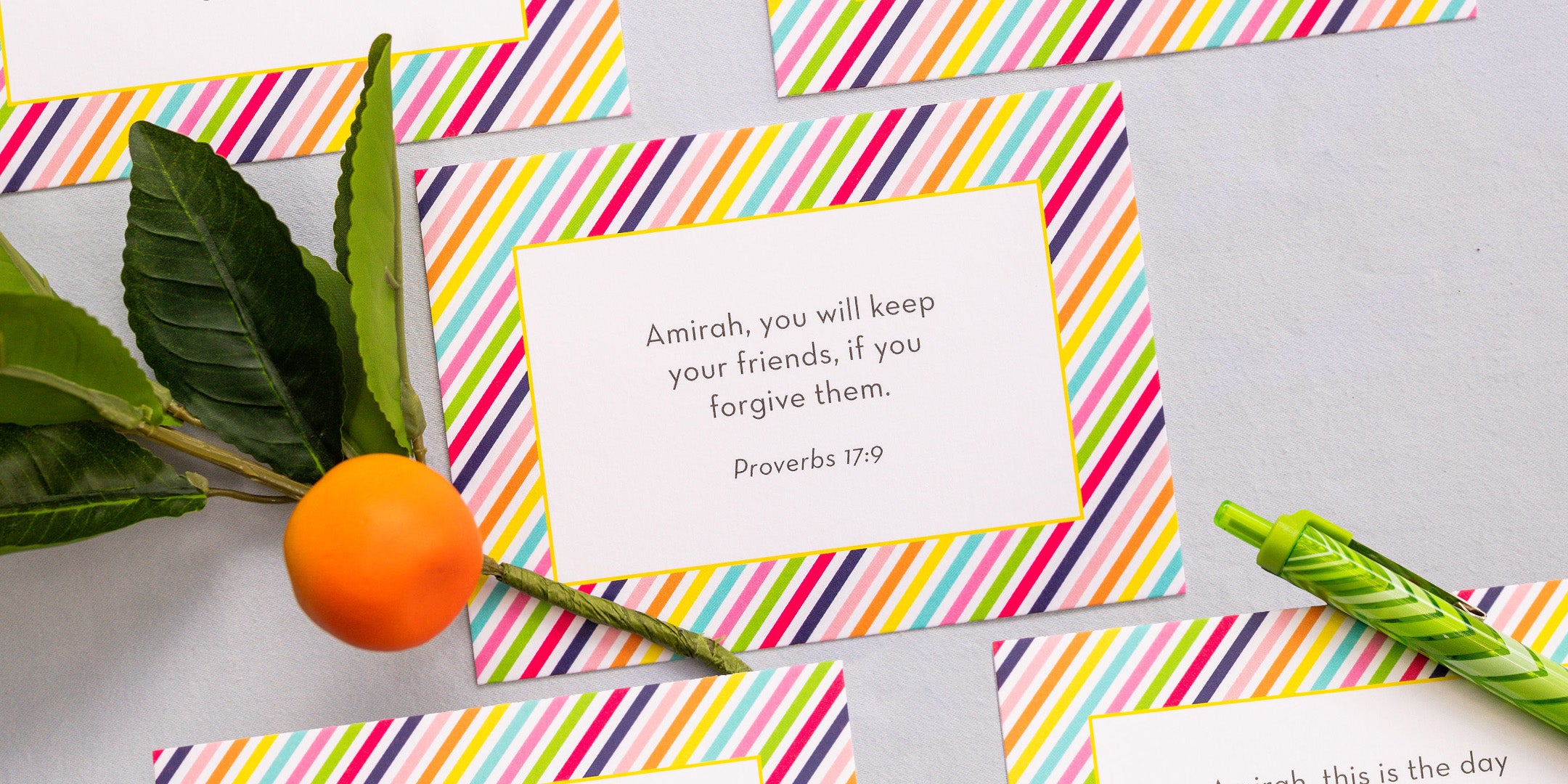 Kids designed personalized scripture cards laid out to see the designs with an orange and leaf 