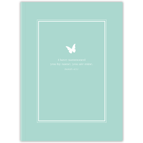 A planner with a light teal cover featuring a white frame and a butterfly design, with personalized scripture verse printed on it.