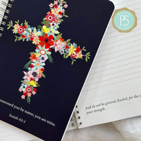 Wire coil personalized scripture journal laid on top of an open page with personalized scripture.