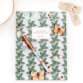 Hardcover Butterfly personalized scripture journal by Lydia Carraway styled with a decorative pen and hairclip, showcasing an elegant journaling setup with a unique curated set of Bible verses