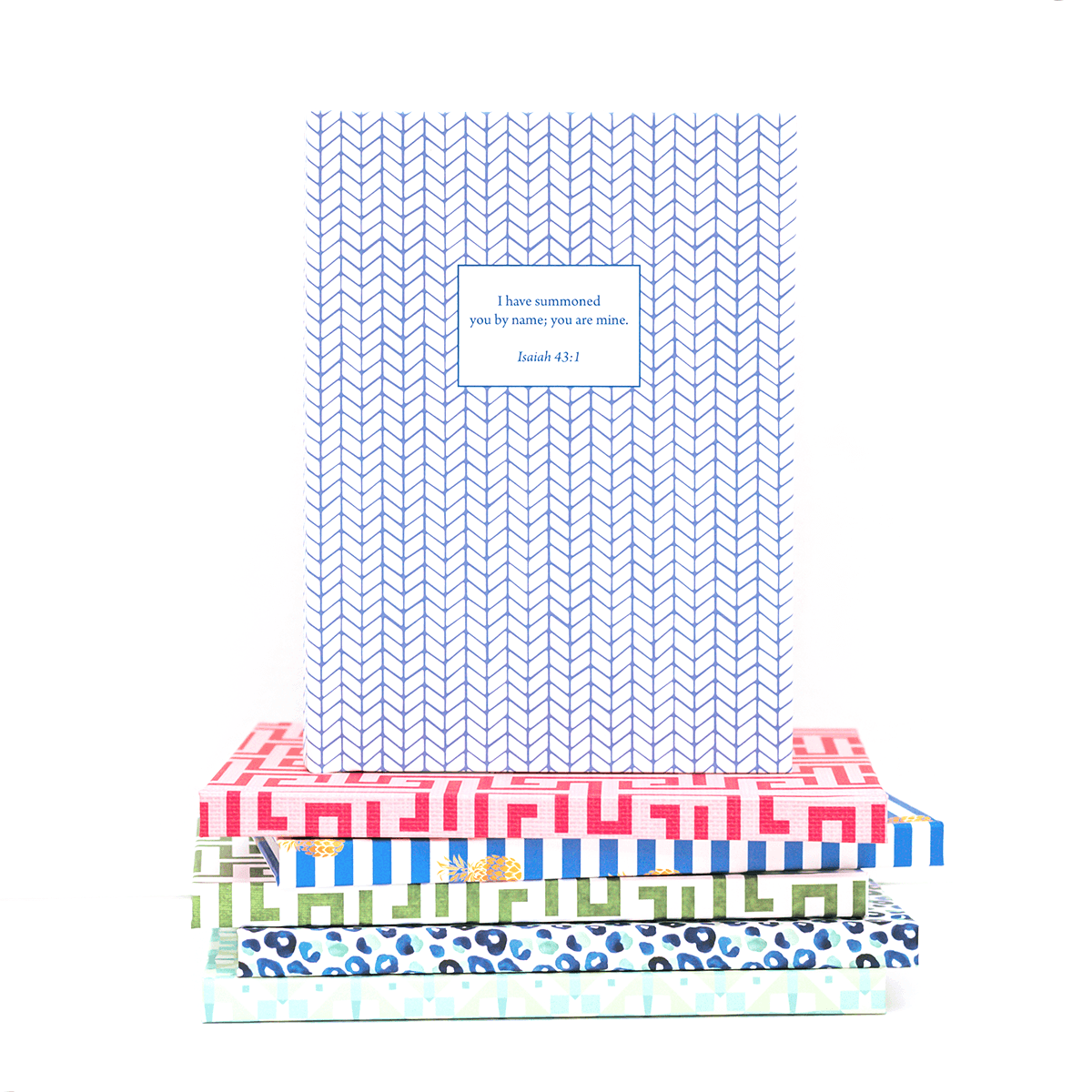Feather design personalized scripture journal placed on top of multiple journals, showcasing a collection of curated Bible verse journals for reflection and gifting
