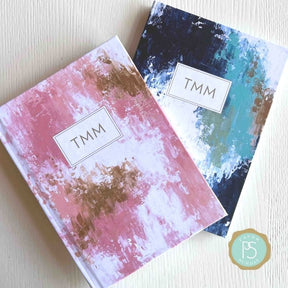 Two personalized scripture journals with artist-designed covers by Theresa Mangum, including the Refresh design, styled in a calm setting for daily reflection and journaling